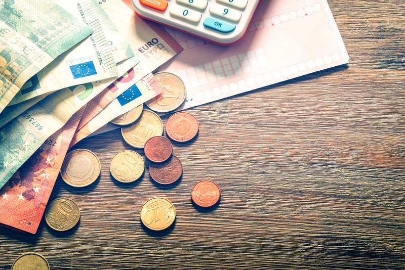 Euro-Banknoten, Rechnung und Taschenrechner auf einem Holztisch.