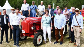 Mehrere Personen stehen um einen alten roten Traktor herum, darunter Landwirtschaftsminister Sven Schulze