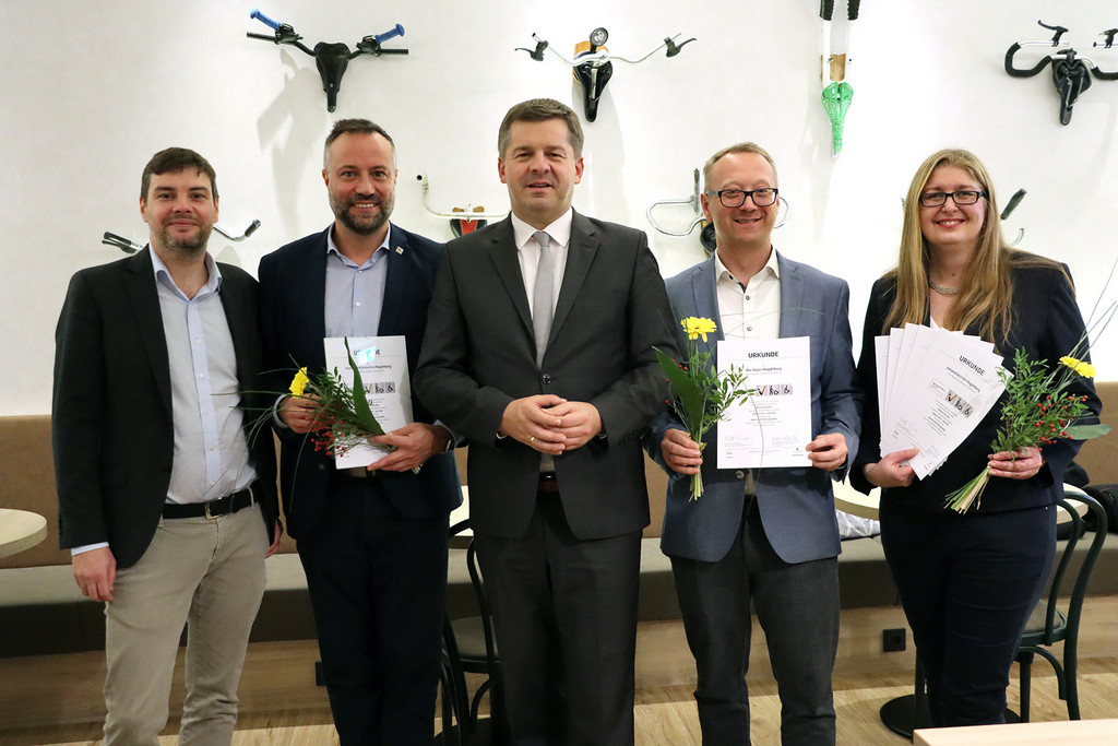 Das Bild zeigt Minister Sven Schulze, Martin Schulze (Geschäftsführer des Tourismusverbandes Sachsen-Anhalt e. V.) und die Empfänger des Gütesiegels