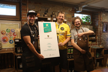 Minister Sven Schulze übergibt das Hofschild für einen "Kulinarischen Stern" an die Kaffeemänner aus Aschersleben.